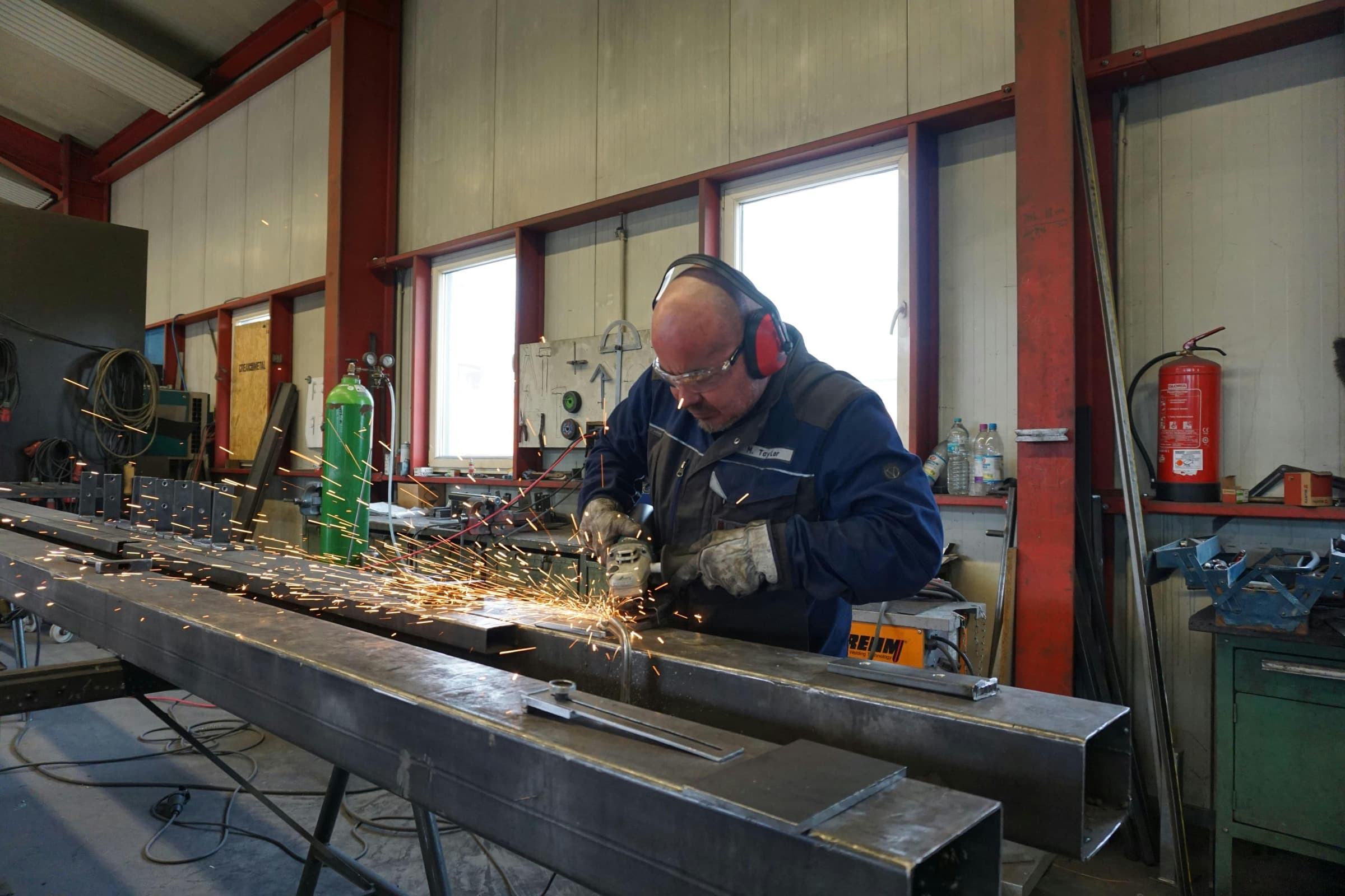 Metallbauer bearbeitet eine Stahlkonstruktion mit einem Winkelschleifer