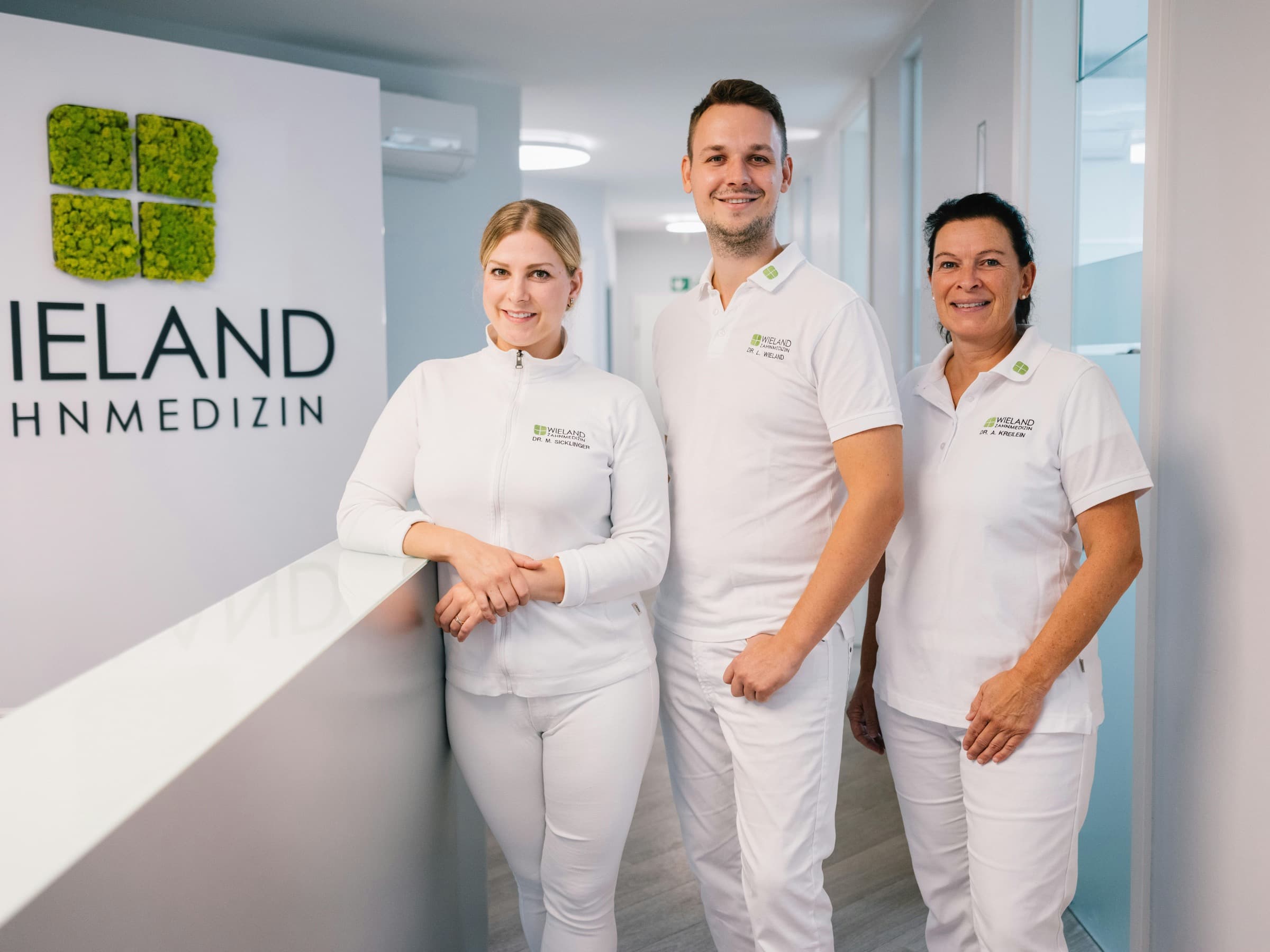 Drei Mitglieder des Teams von WIELAND Zahnmedizin am Empfang der Praxis